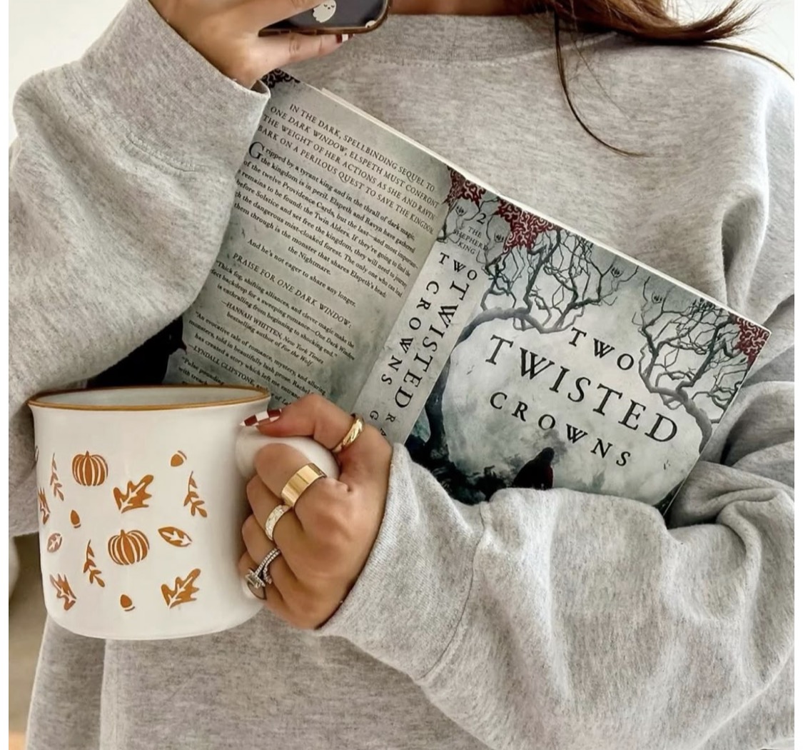 Mulher segurando um livro e uma caneca